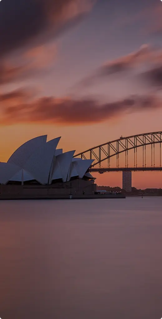 Sydney Opera House and Harbour Bridge at sunset with colorful sky reflections